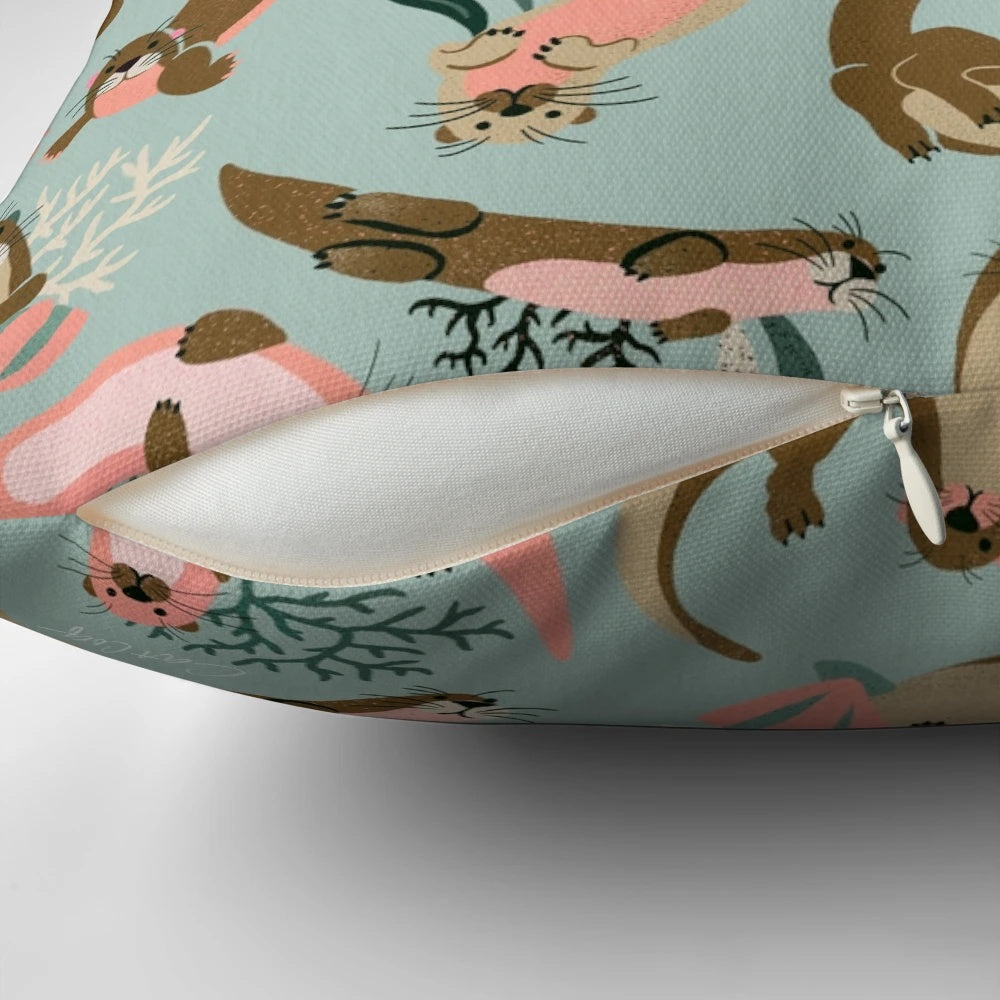 A mint-colored decorative pillow featuring adorable otters swimming in the ocean.