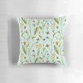 Mint-colored pillow with a design featuring bees, wildflowers, and botanicals