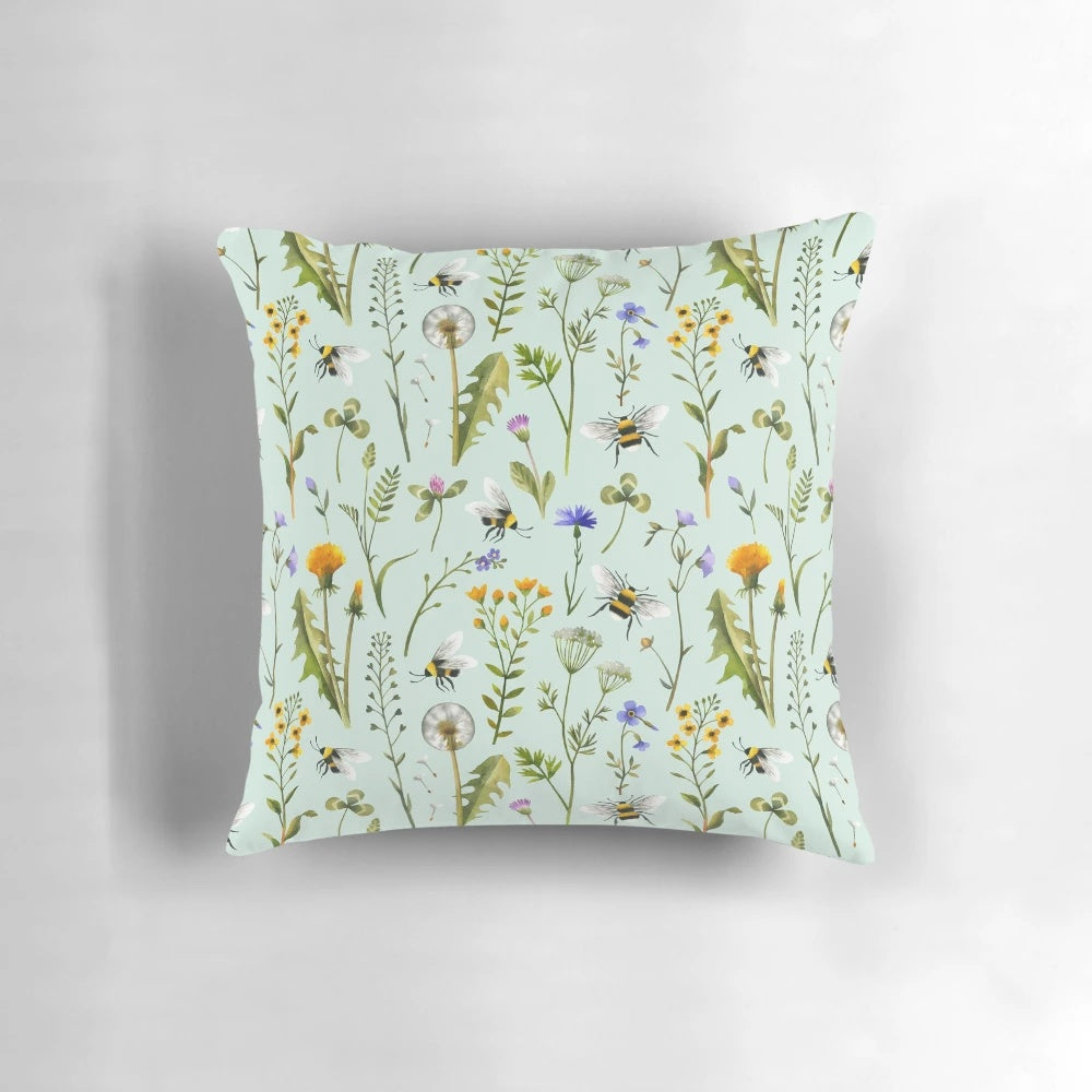 Mint-colored pillow with a design featuring bees, wildflowers, and botanicals
