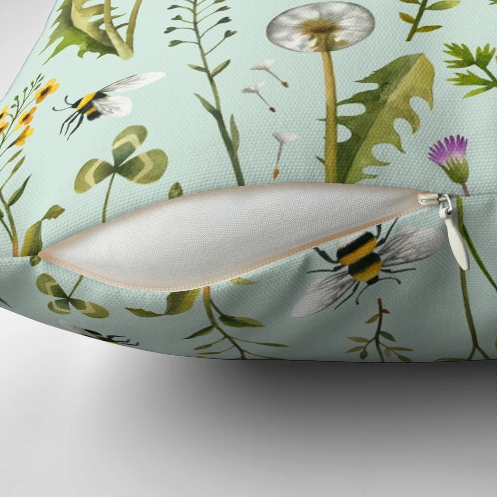 Mint-colored pillow with a design featuring bees, wildflowers, and botanicals