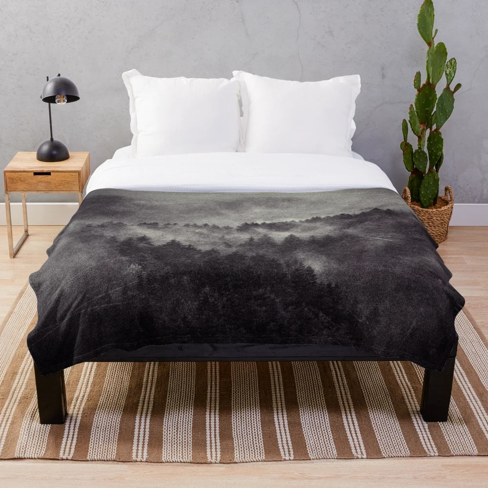 Plush blanket featuring a misty forest scene with trees covered in fog