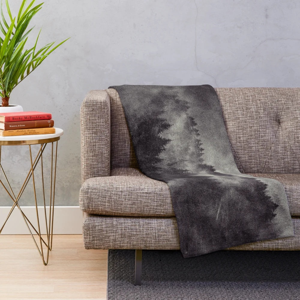 Plush blanket featuring a misty forest scene with trees covered in fog