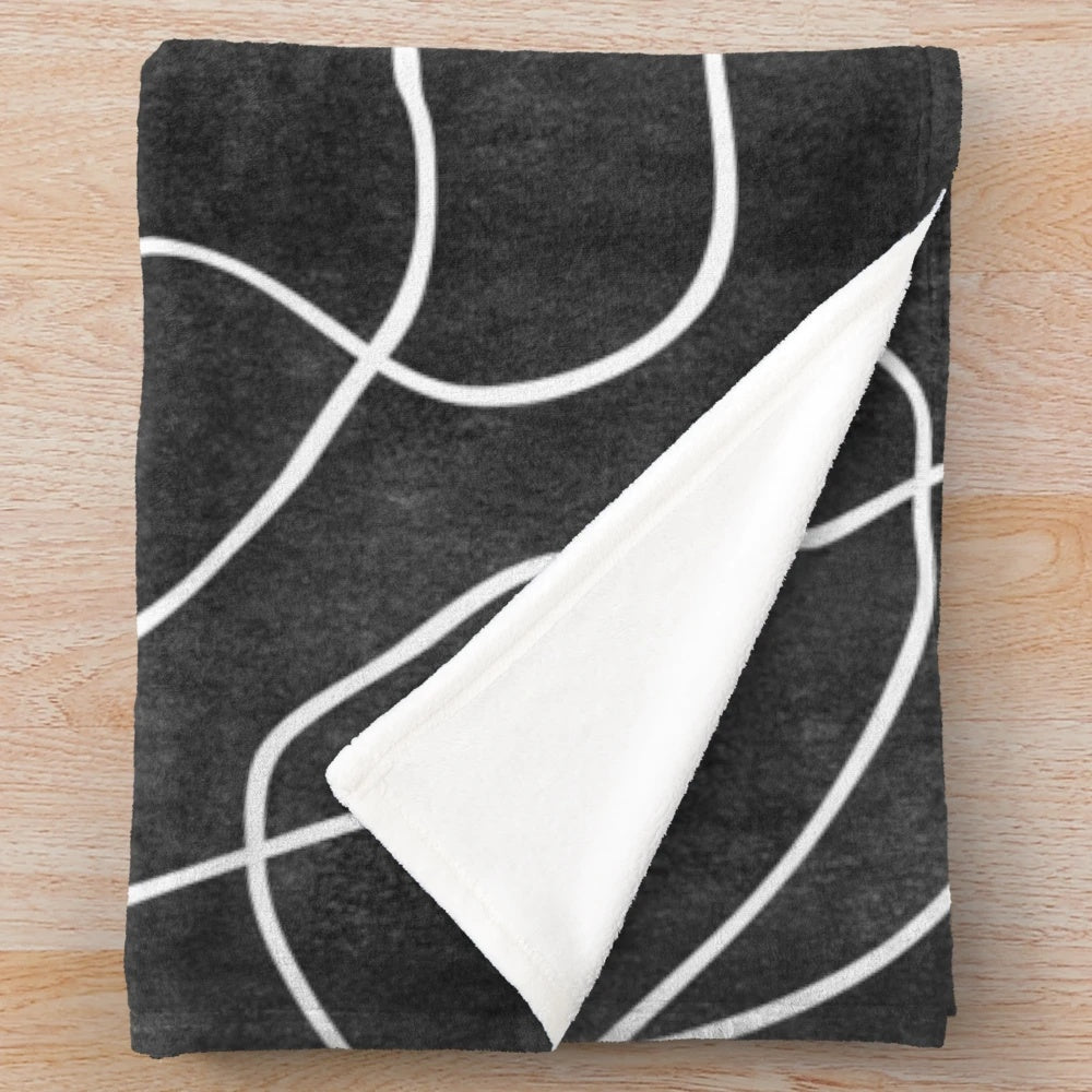 A soft and cozy plush blanket featuring abstract line art faces in a modern, minimalistic black and white design.