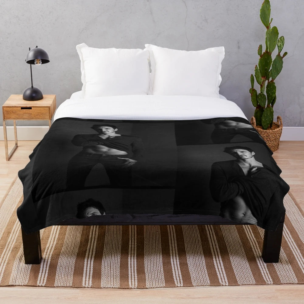 Striking black and white portrait of actor Pedro Pascal on a plush blanket