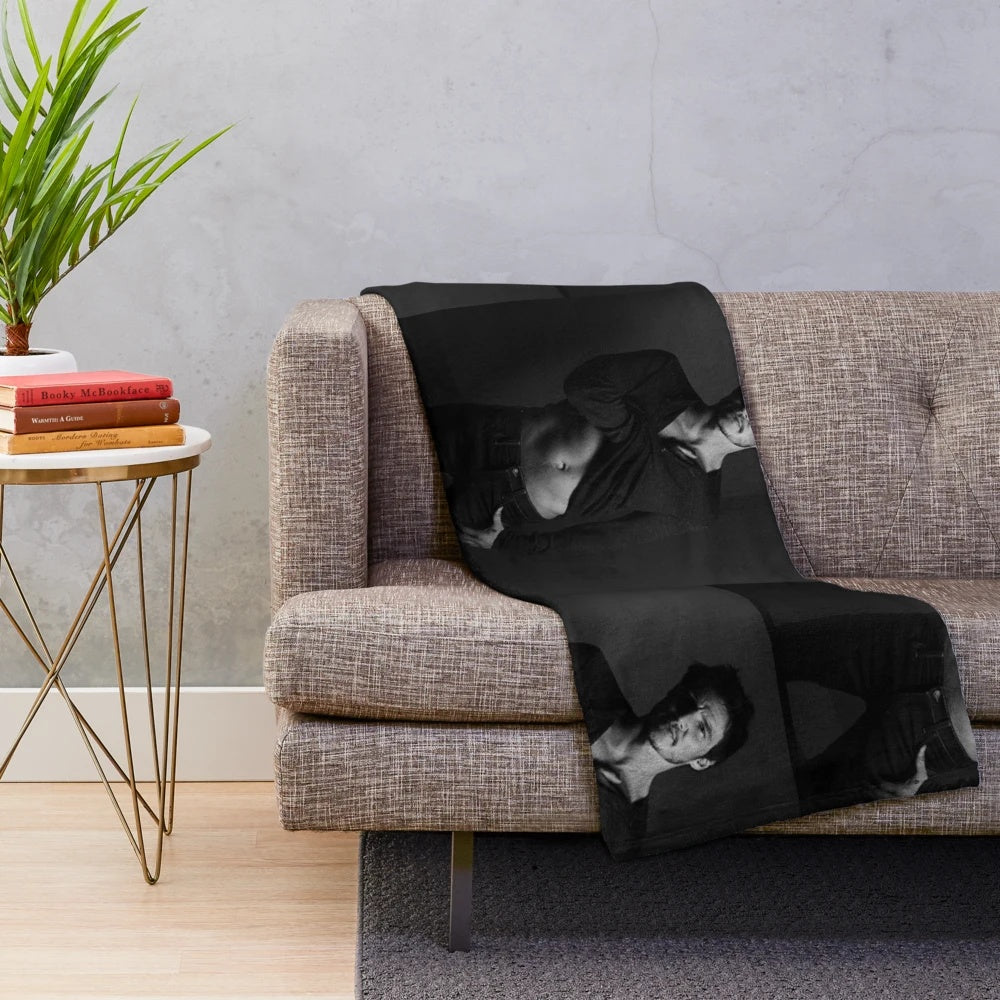 Striking black and white portrait of actor Pedro Pascal on a plush blanket