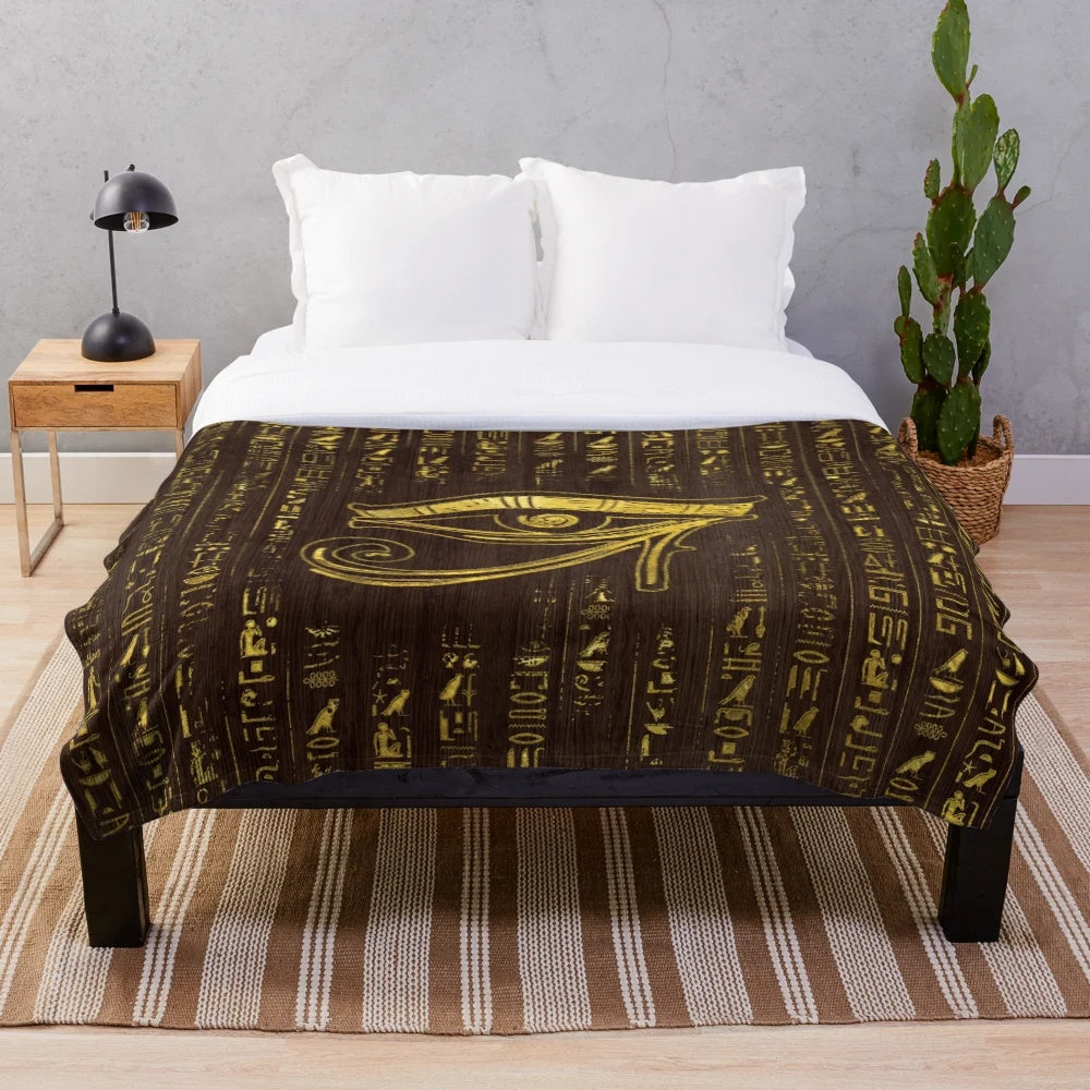 Plush blanket featuring the ancient Egyptian Eye of Horus and hieroglyphics on a wooden background