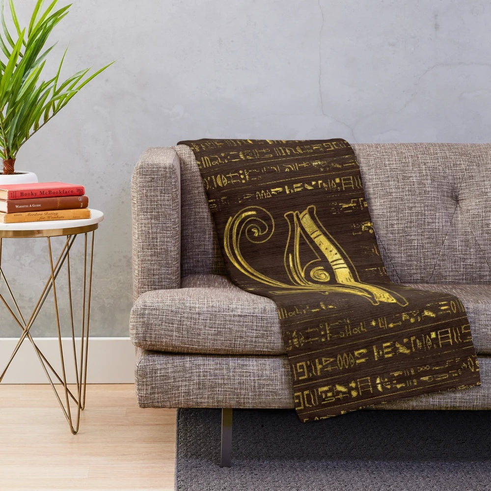 Plush blanket featuring the ancient Egyptian Eye of Horus and hieroglyphics on a wooden background
