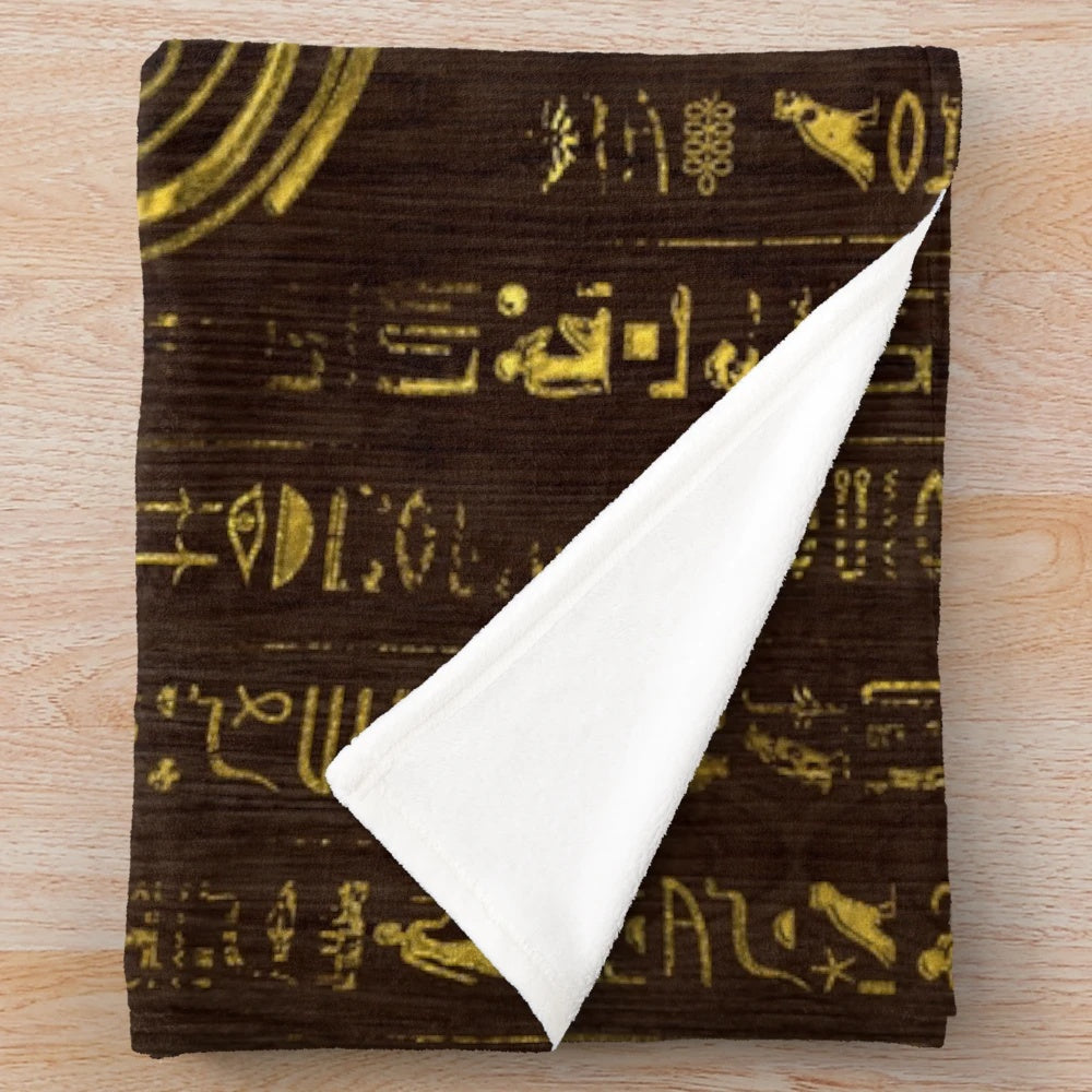 Plush blanket featuring the ancient Egyptian Eye of Horus and hieroglyphics on a wooden background