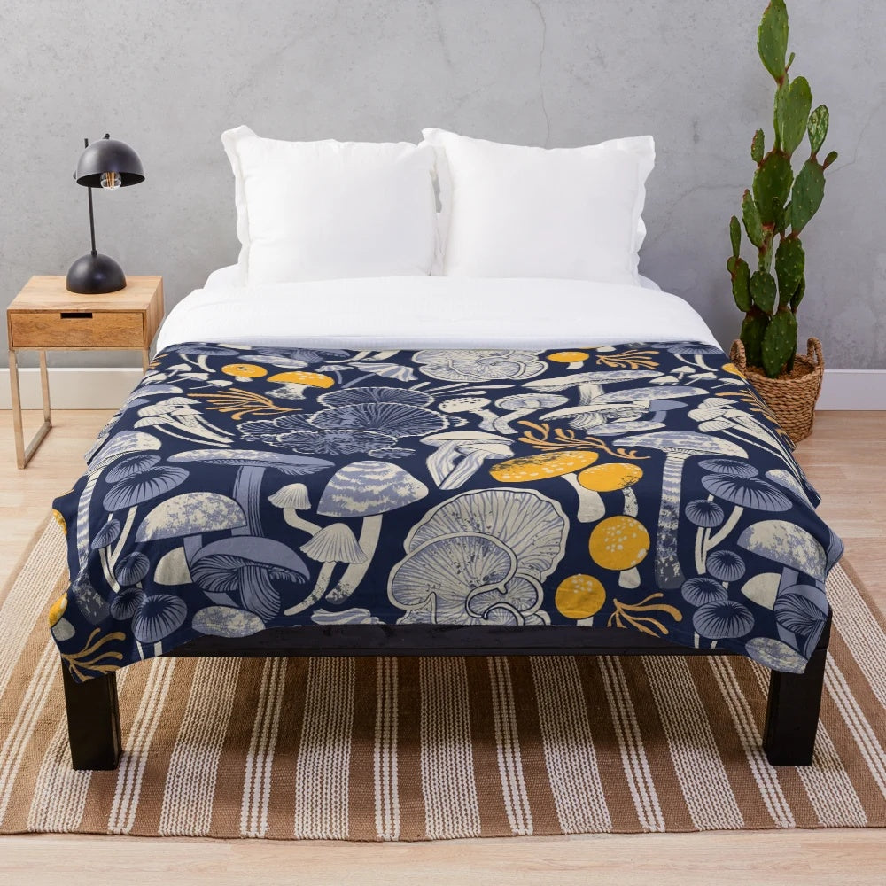 Mystical fungi plush blanket featuring ivory, pale blue, and yellow wild mushrooms on a midnight blue background