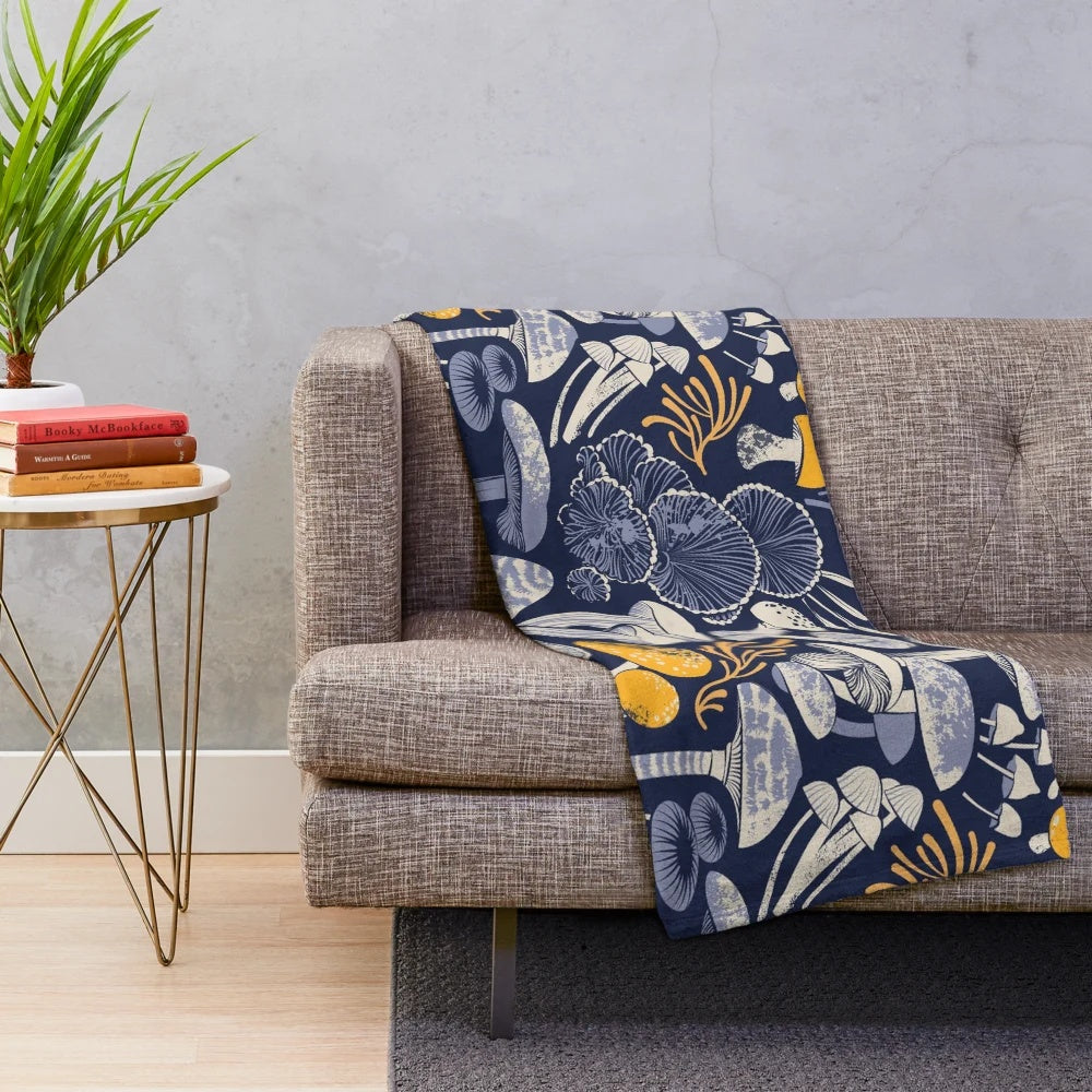 Mystical fungi plush blanket featuring ivory, pale blue, and yellow wild mushrooms on a midnight blue background