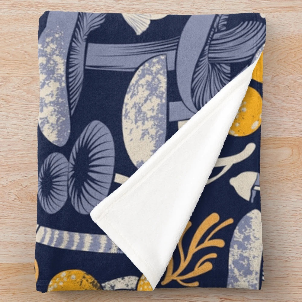 Mystical fungi plush blanket featuring ivory, pale blue, and yellow wild mushrooms on a midnight blue background