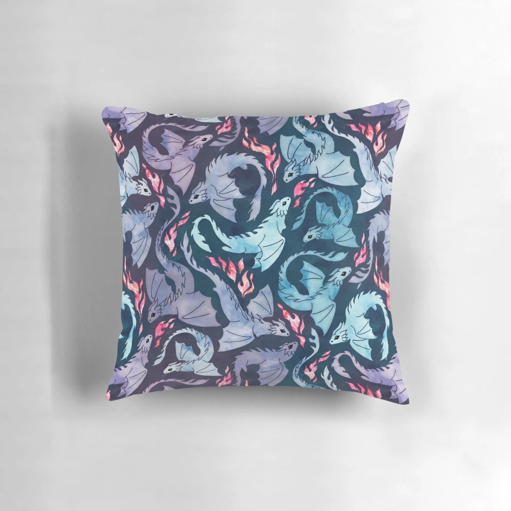 A decorative throw pillow featuring a watercolor-style illustration of a fire-breathing dragon in shades of turquoise and purple.