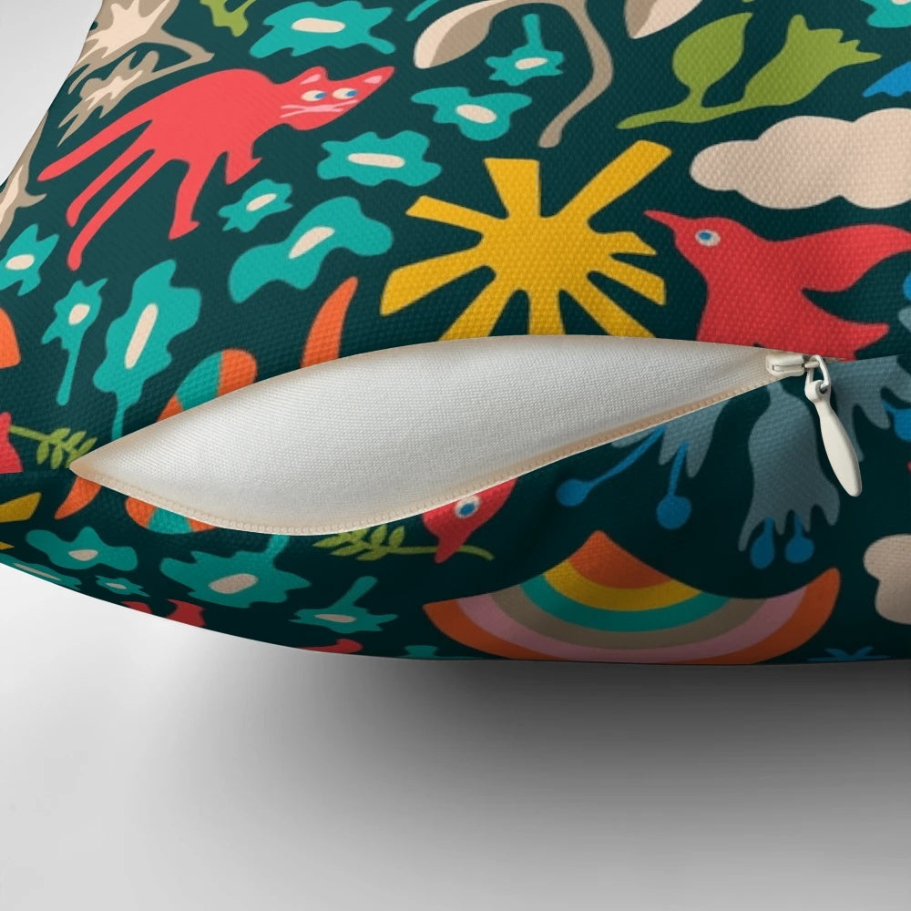 A colorful, nature-themed decorative pillow featuring birds, animals, flowers, rainbows, and clouds on a dark teal background.