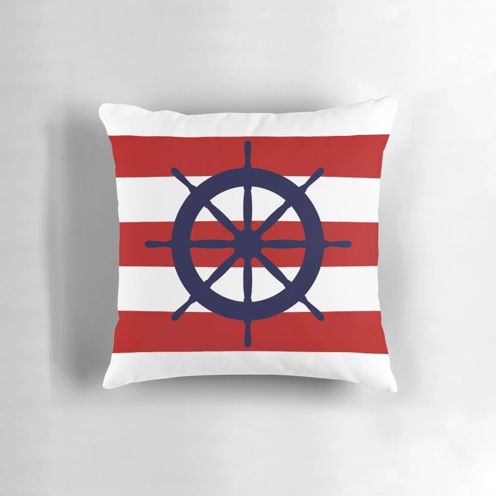 A nautical-themed accent pillow featuring a navy blue and red striped design with a ship's steering wheel in the center.