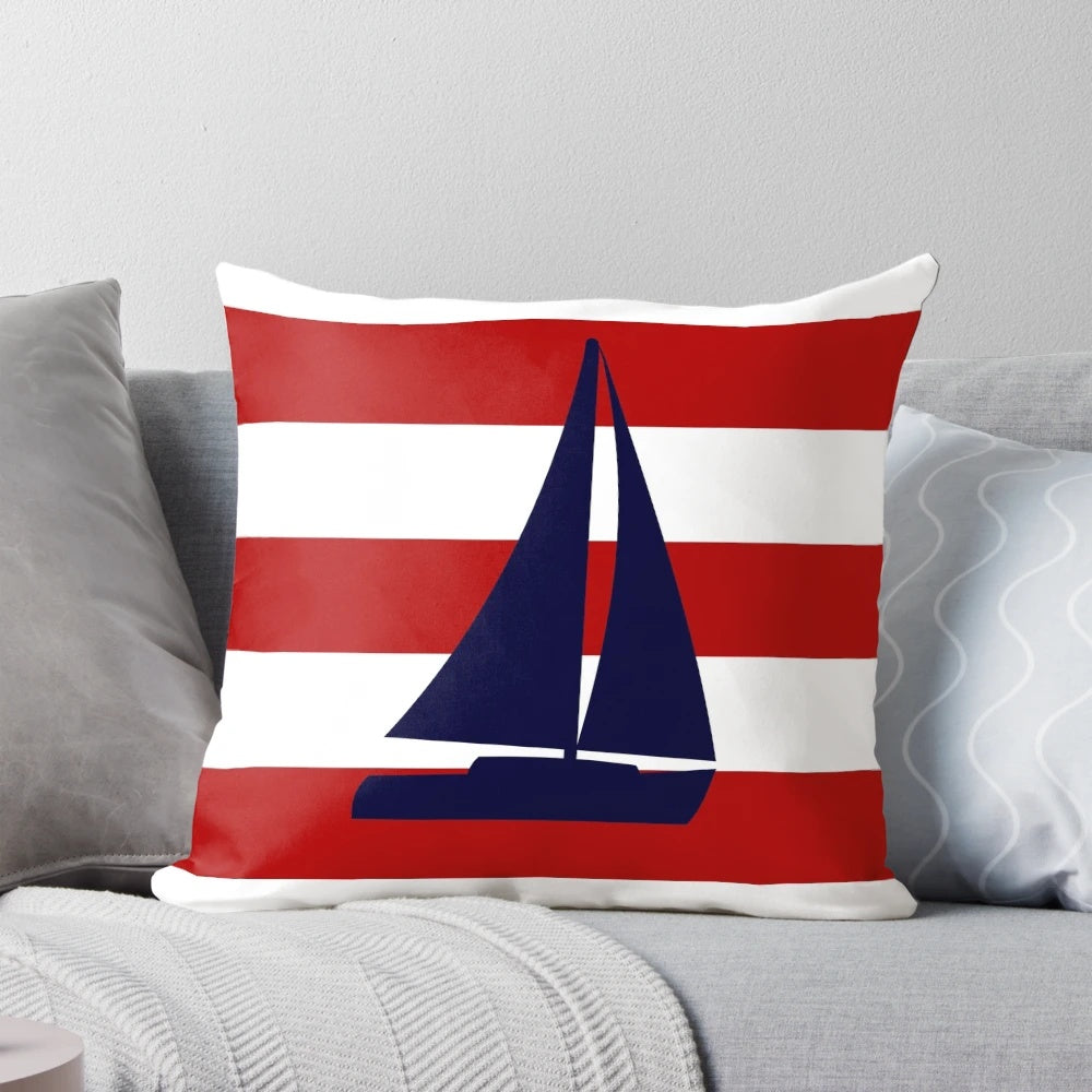 A navy blue pillow featuring a sailboat design against red and white striped background