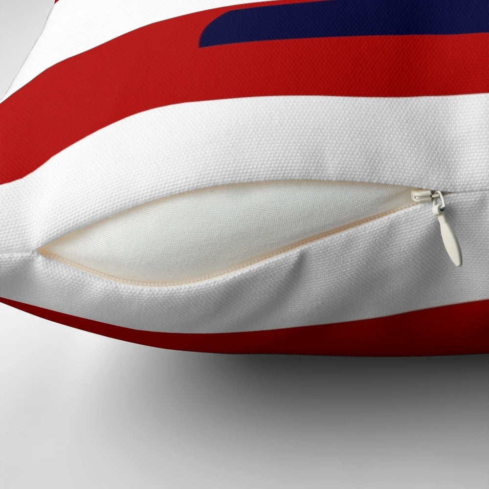 A navy blue pillow featuring a sailboat design against red and white striped background