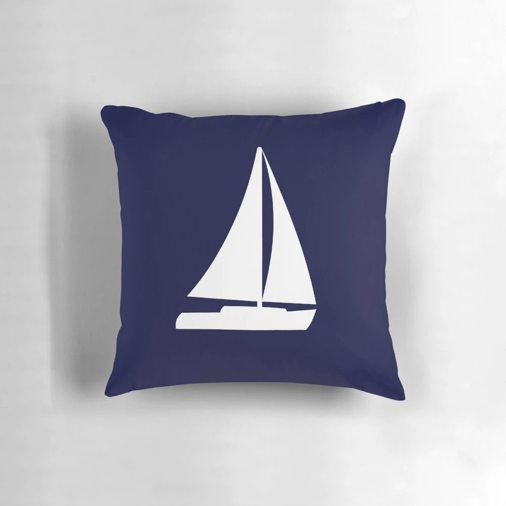 Decorative navy blue pillow with white sailboat silhouette, perfect for nautical-themed home decor