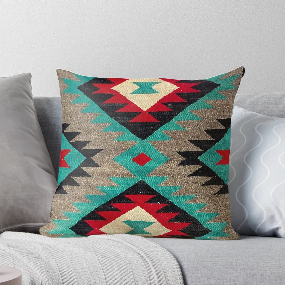 A decorative throw pillow featuring a vibrant Navajo-inspired pattern in shades of turquoise, red, grey, and black.