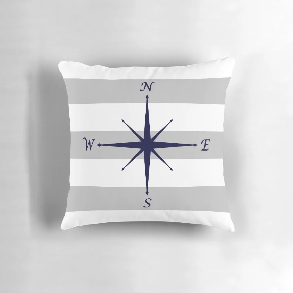 Navy blue compass motif on a silver gray and white striped decorative throw pillow.