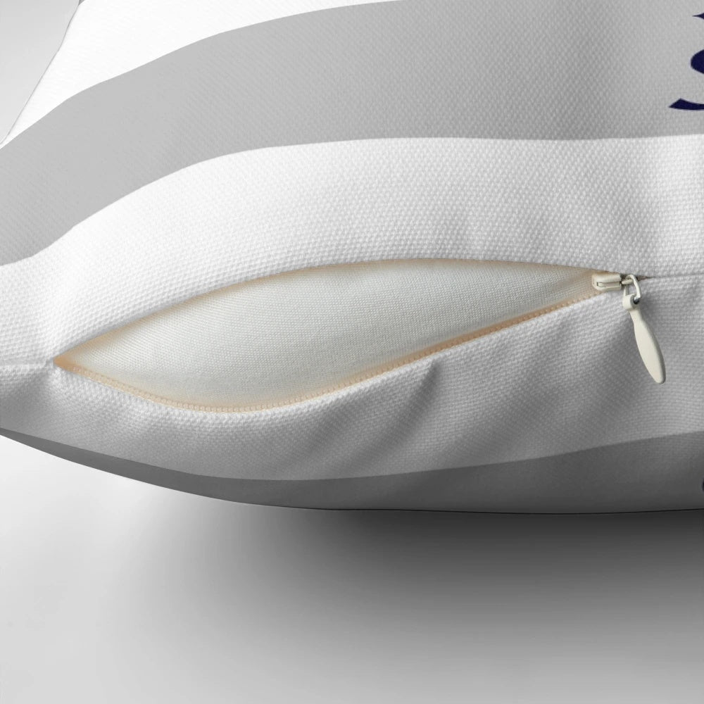 Navy blue compass motif on a silver gray and white striped decorative throw pillow.