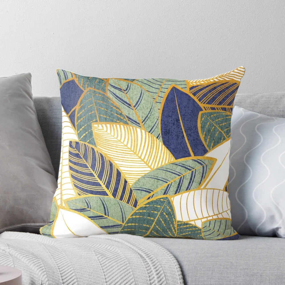 Decorative throw pillow with navy blue, pine, and sage green leaves with golden lines