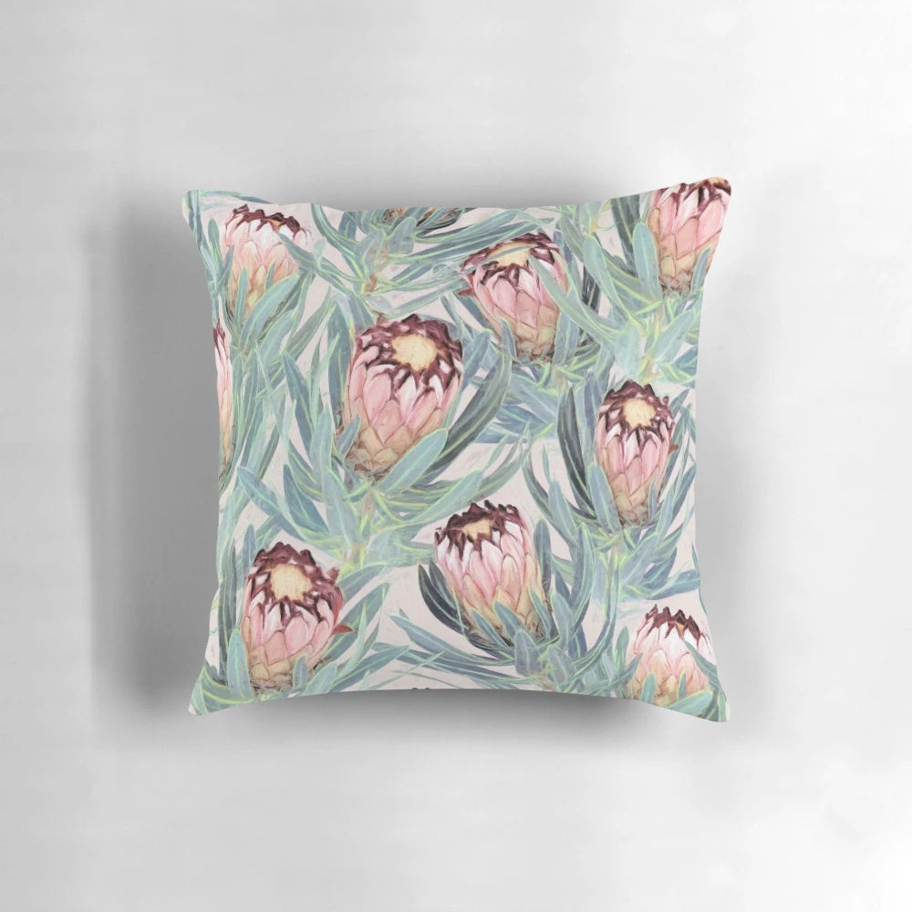 Vibrant painted protea neriifolia flower pattern on a soft, dusty pink decorative pillow