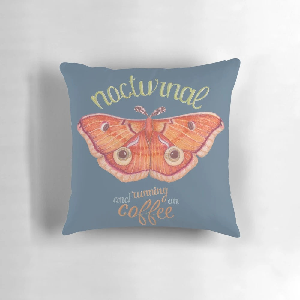 Pillow featuring a nocturnal orange moth resting on a cup of coffee against a dark background with handlettered typography.