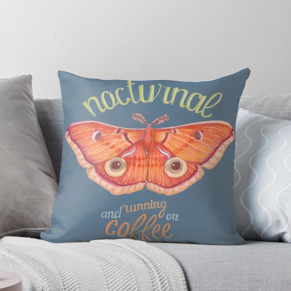Pillow featuring a nocturnal orange moth resting on a cup of coffee against a dark background with handlettered typography.
