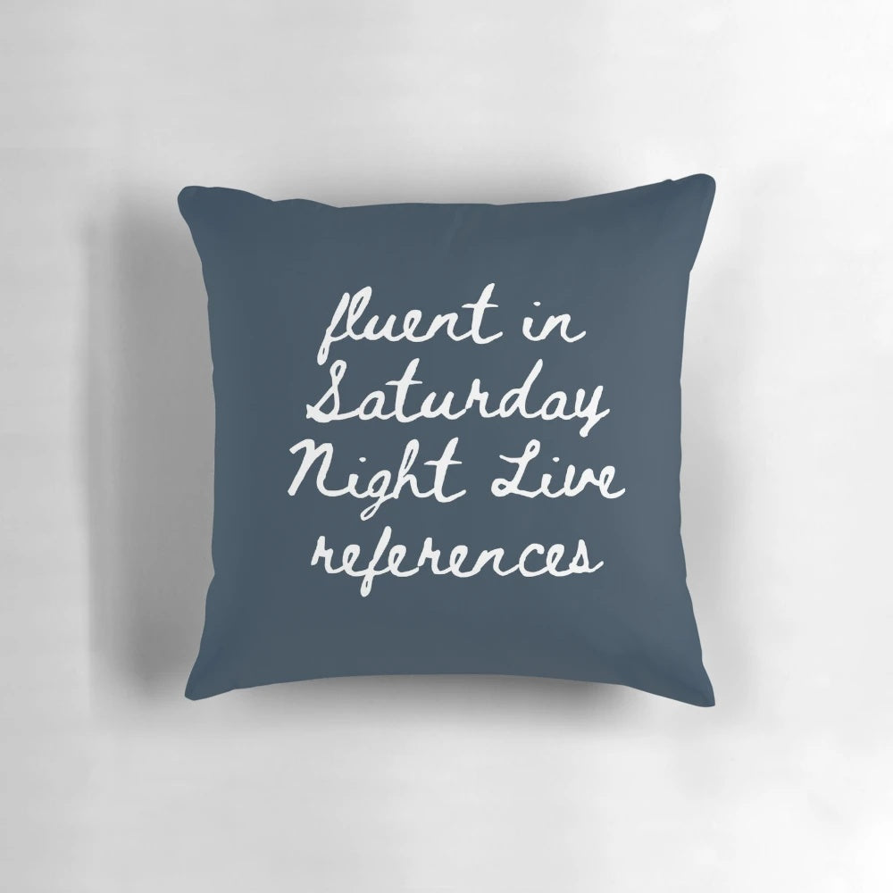 A grey and black pillow with various New York City and Saturday Night Live-inspired icons and designs.