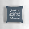 A grey and black pillow with various New York City and Saturday Night Live-inspired icons and designs.