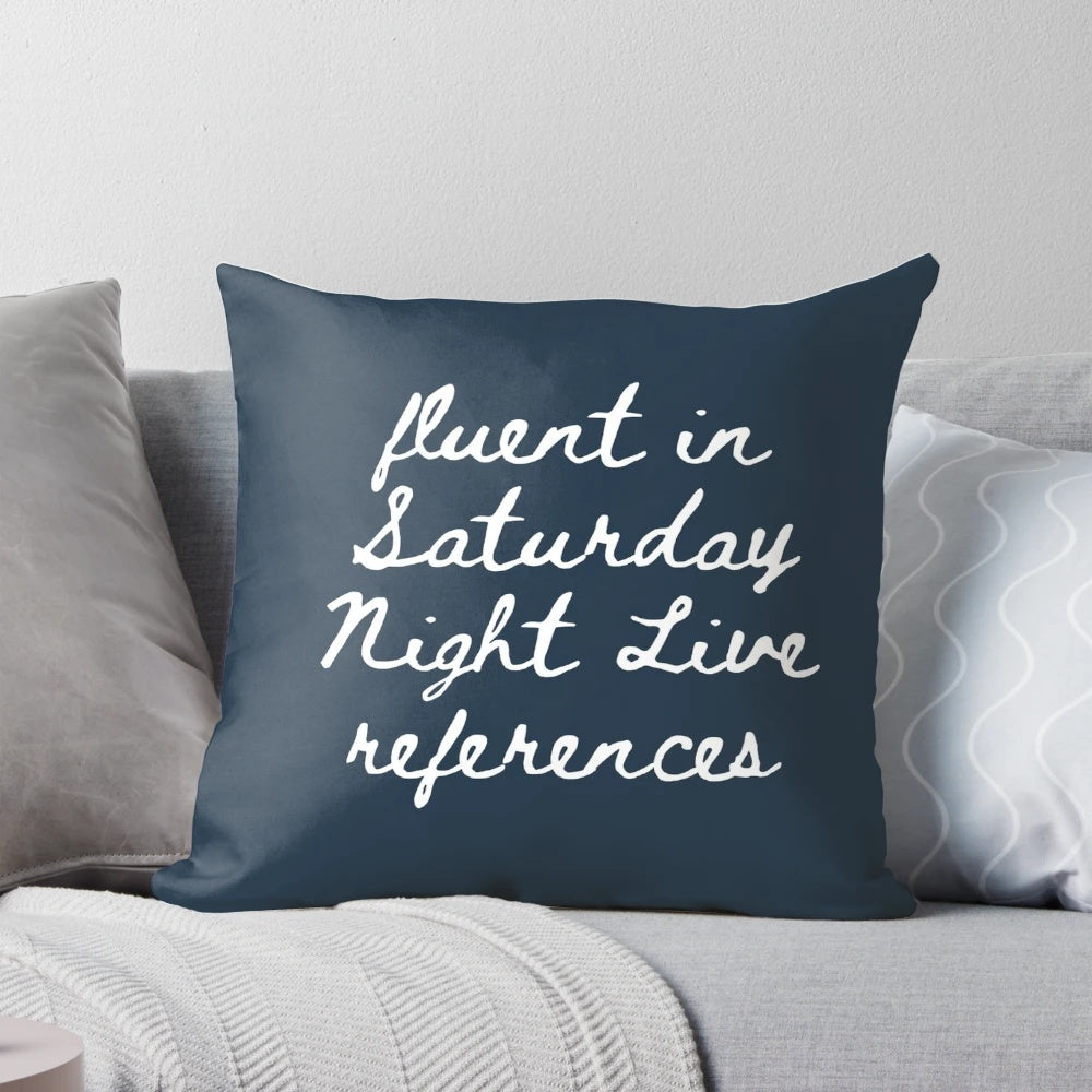 A grey and black pillow with various New York City and Saturday Night Live-inspired icons and designs.