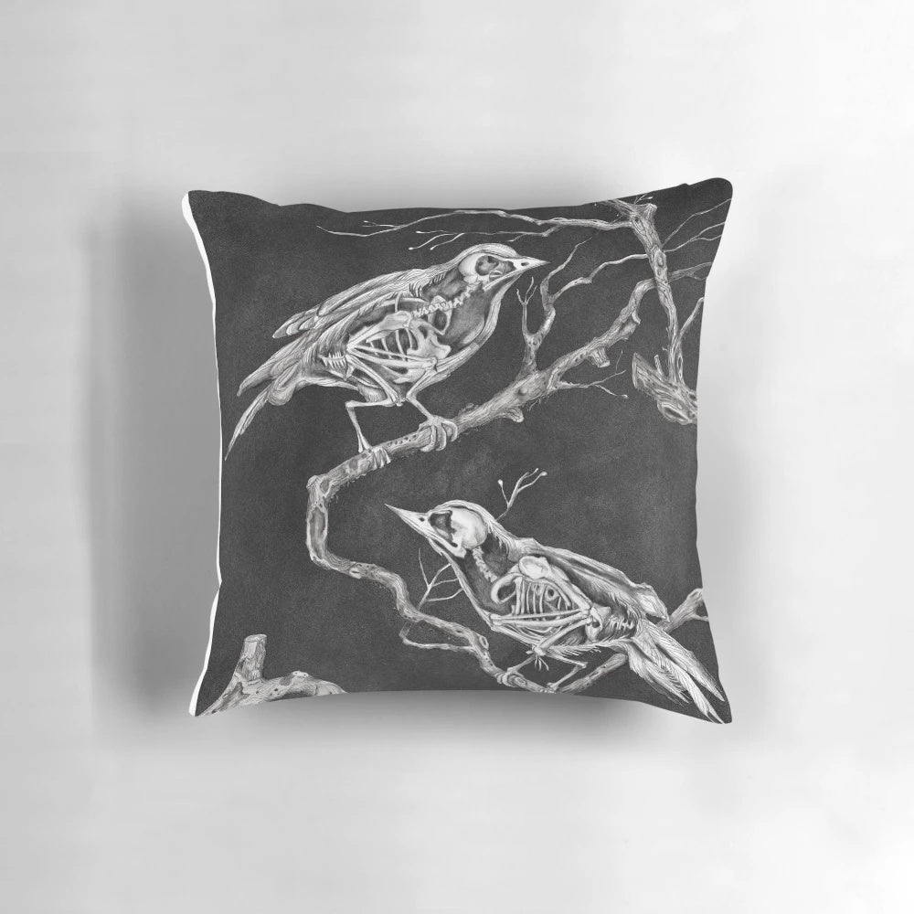 A black and white pillow design featuring a skeleton and birds, conveying a sense of melancholy and forgetfulness.