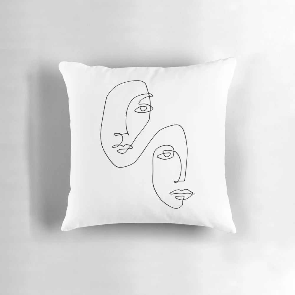 A pillow featuring a simple, continuous line art depiction of a minimalist face design.