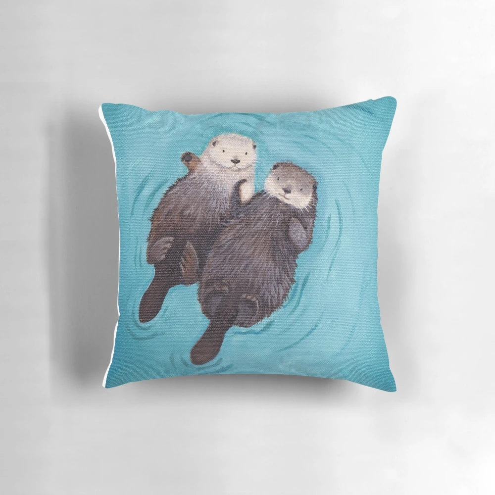 Soft, plush pillow featuring a pair of adorable sea otters holding hands, perfect for romantic home decor.