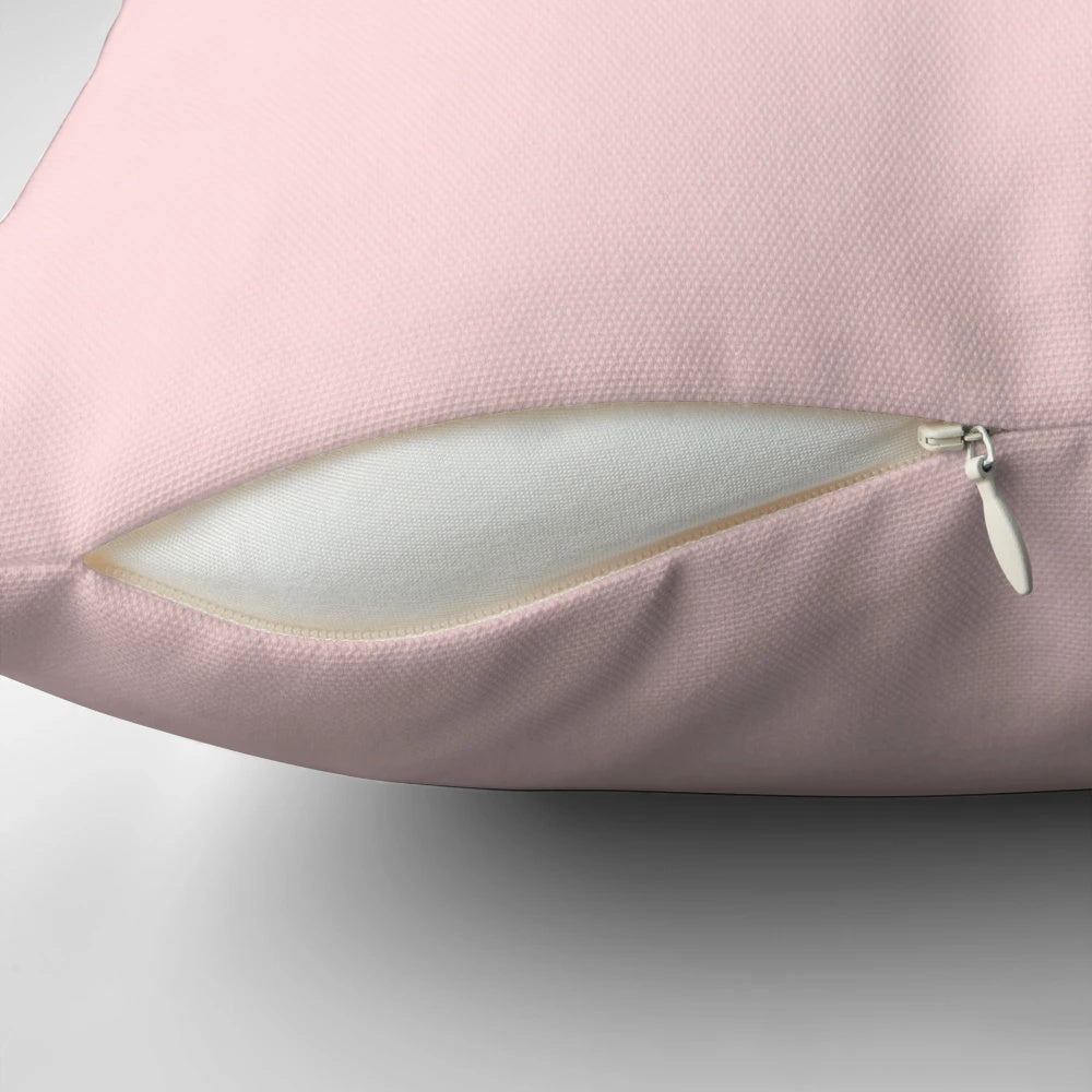 Pastel pink and blush colored pillow with small text, evoking a minimalist, California desert aesthetic.
