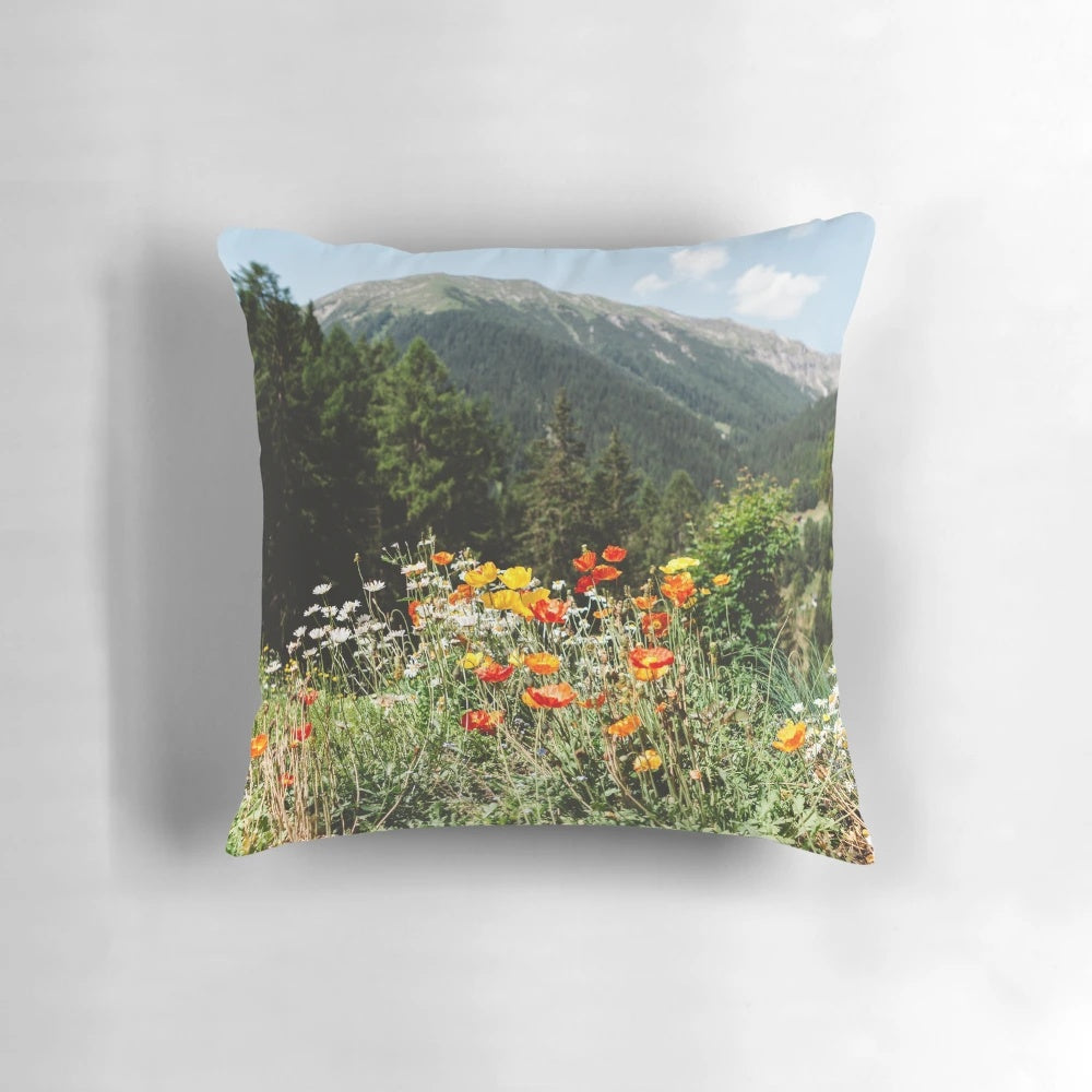 A cozy mountain garden pillow featuring vibrant wildflowers and a serene landscape.