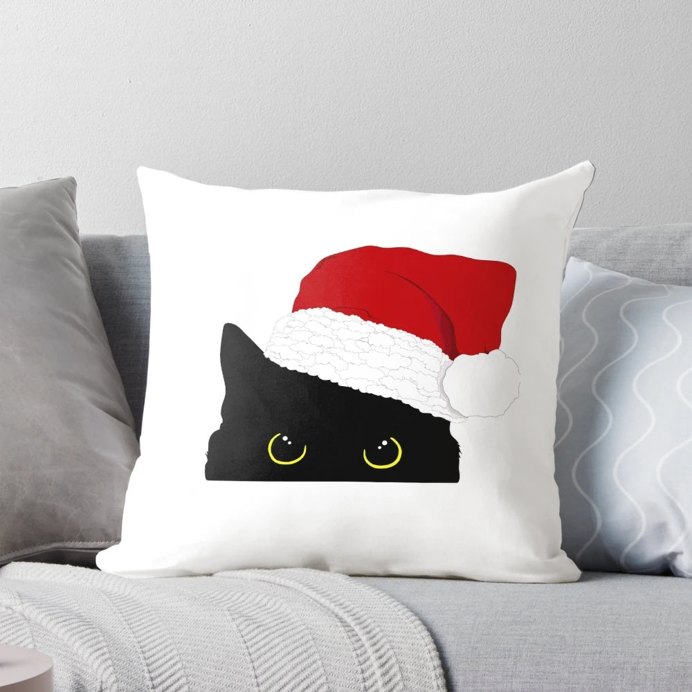 A cozy black cat peeking out from a Christmas pillow with a Santa Claus silhouette