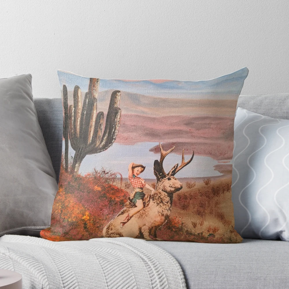 Decorative throw pillow featuring a pinup-style jackalope cowgirl on a cactus-filled desert background.