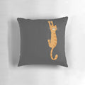 An orange tabby cat hanging onto a pillow with a humorous and whimsical design.