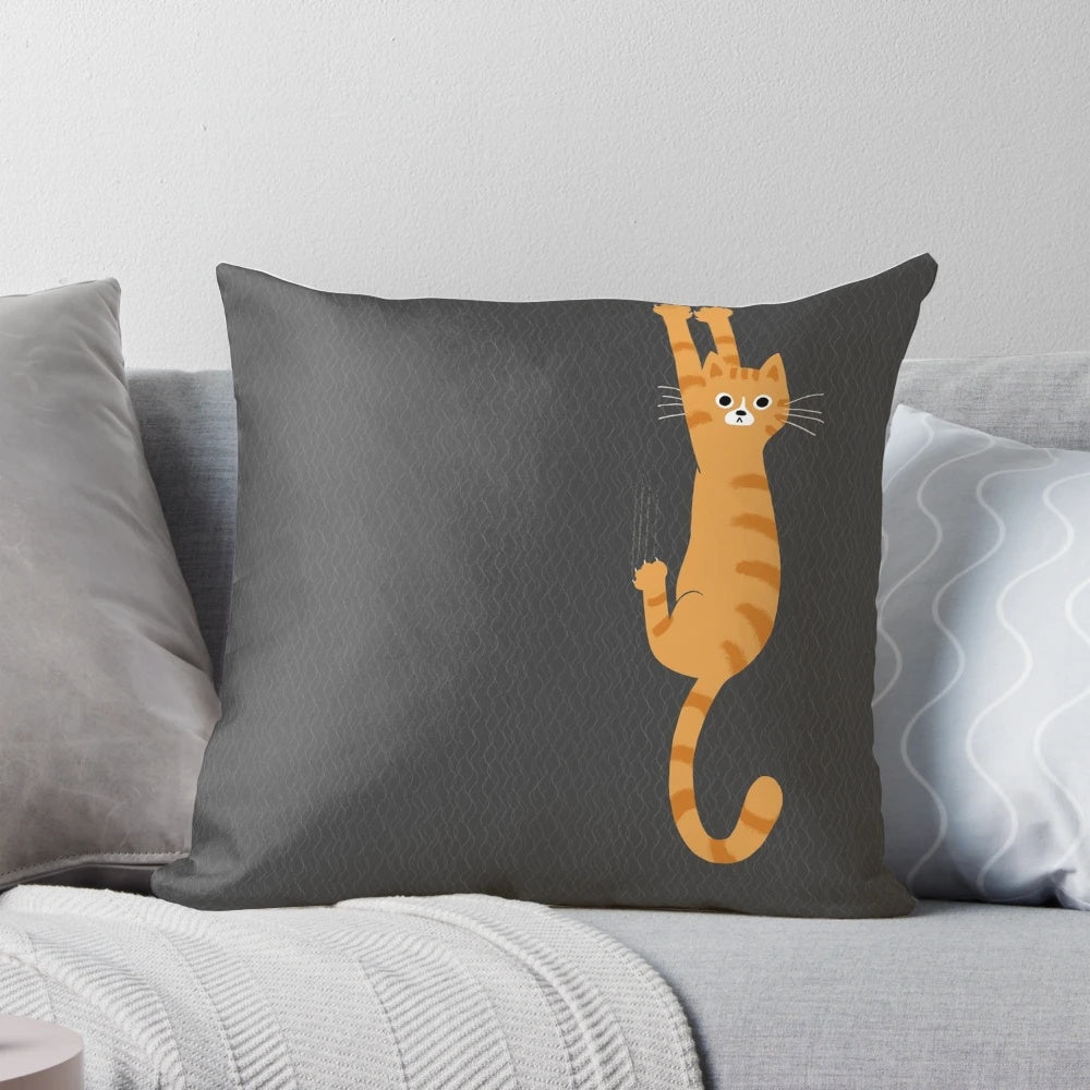 An orange tabby cat hanging onto a pillow with a humorous and whimsical design.