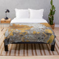 Plush blanket with faux metalfoil gold design on gray concrete wall background