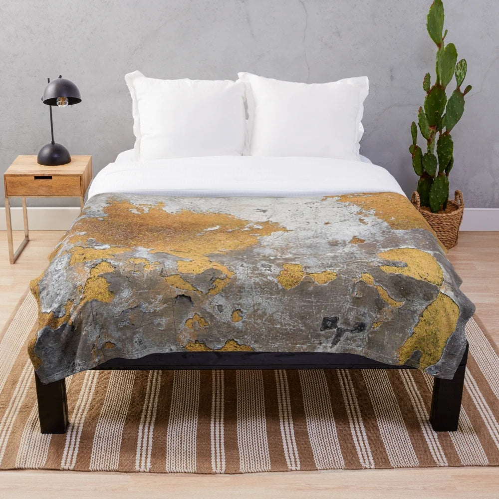 Plush blanket with faux metalfoil gold design on gray concrete wall background