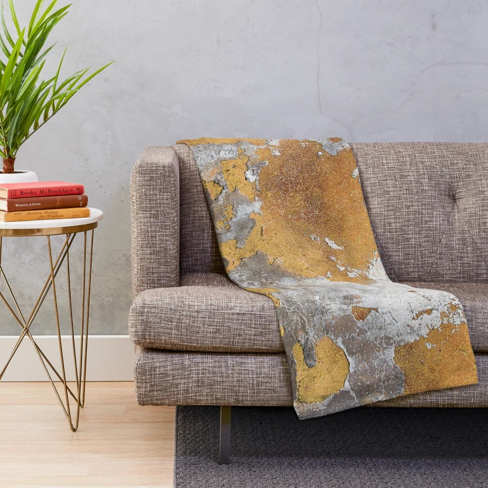Plush blanket with faux metalfoil gold design on gray concrete wall background