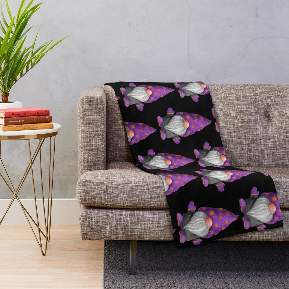 A cozy plush blanket featuring a cute gnome design with orange and purple polka dots, perfect for autumn and Halloween decor.