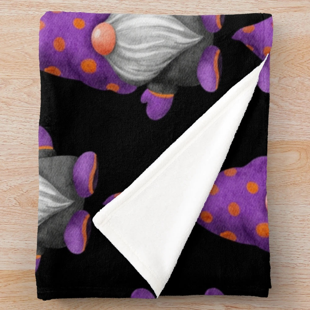 A cozy plush blanket featuring a cute gnome design with orange and purple polka dots, perfect for autumn and Halloween decor.