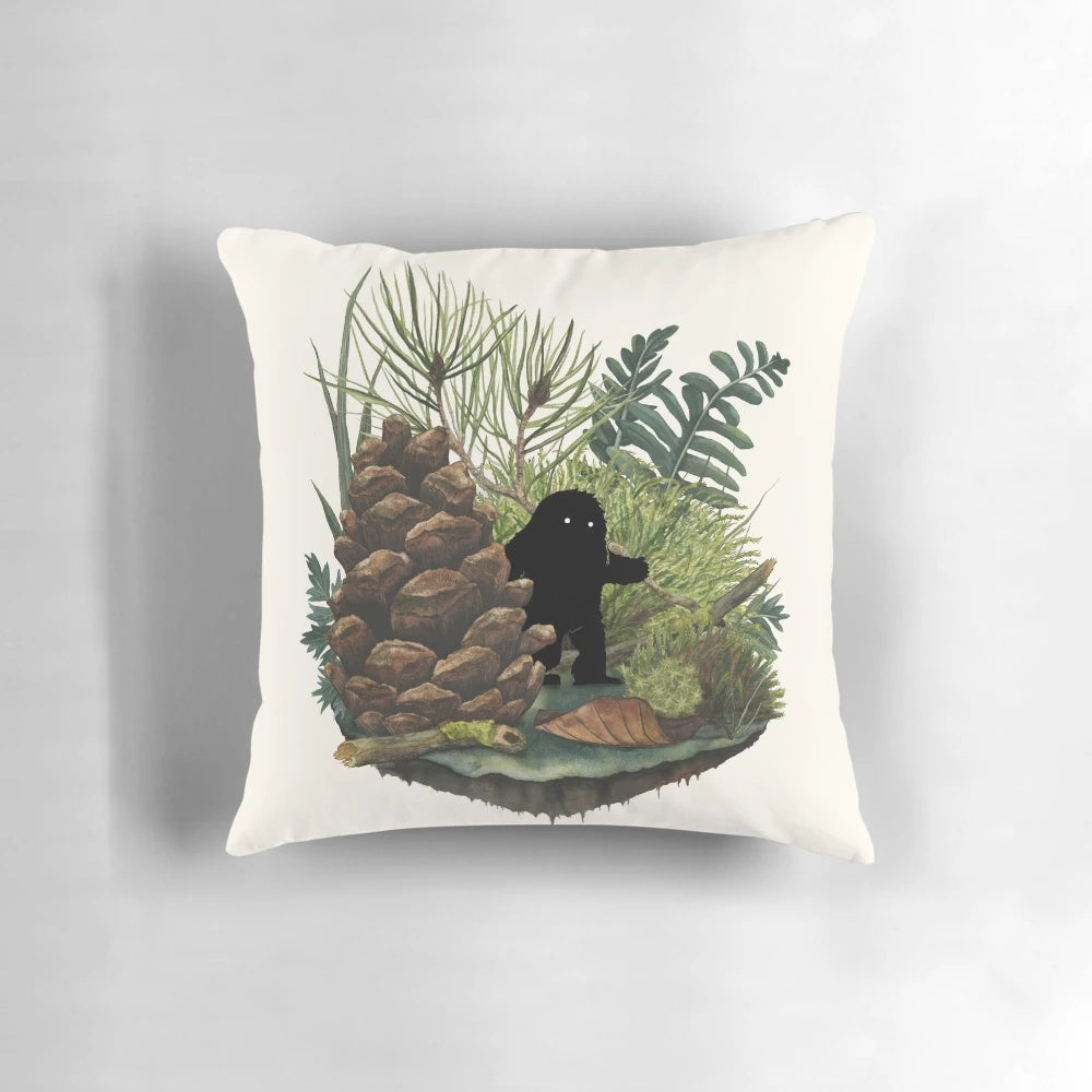 A soft, plush pillow featuring a whimsical watercolor illustration of a tiny sasquatch or woodland creature.