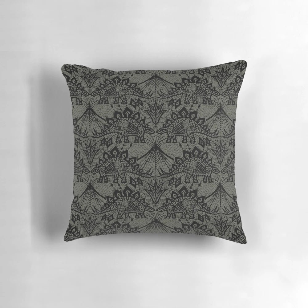 A decorative throw pillow featuring a detailed stegosaurus dinosaur design in a vintage lace pattern with black and grey colors.
