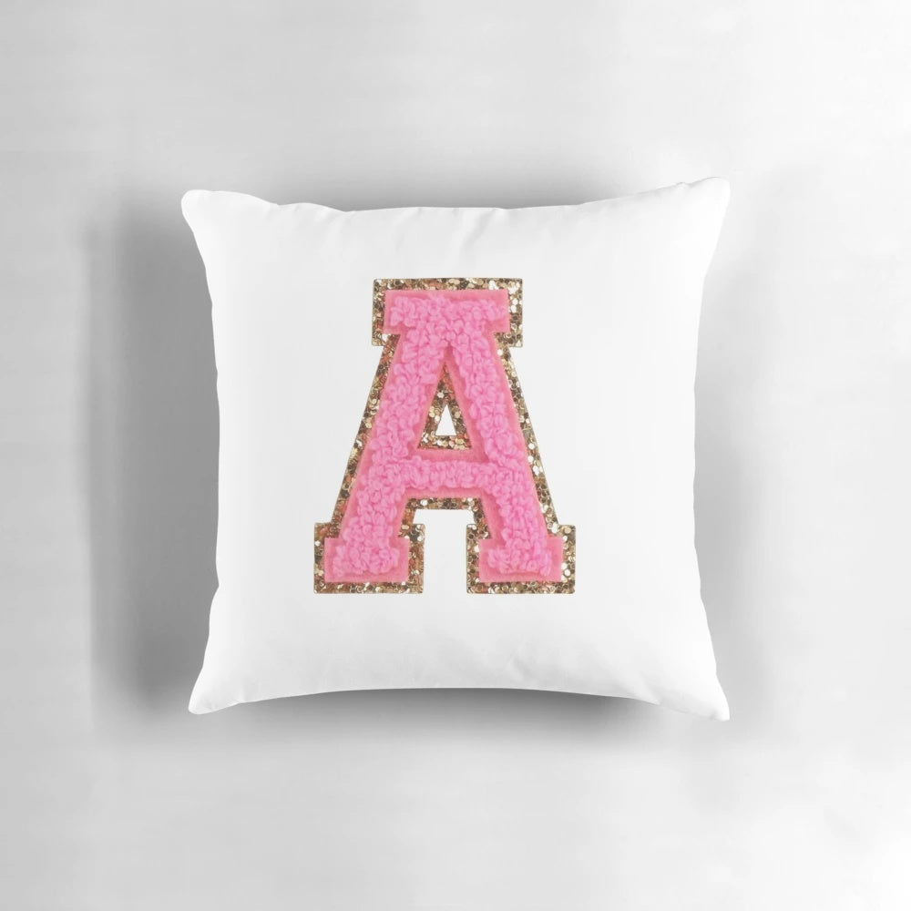 A pink pillow with a preppy letter design, perfect for a stoney clover lane inspired room.