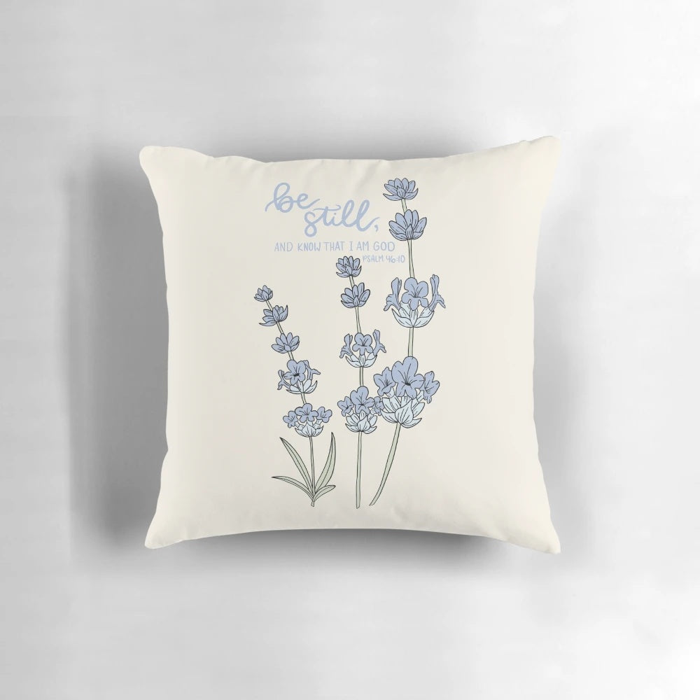 Blue and white hydrangea flowers with the Bible verse "Be still, and know that I am God" from Psalm 46:10 printed on a white pillow.