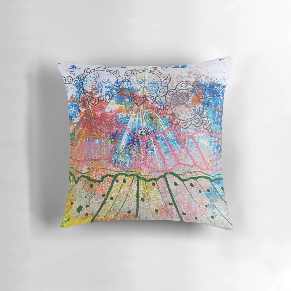 Vibrant abstract watercolor landscape design with radiating blue, green, and pink brush strokes and swirling yellow circles on a pillow.
